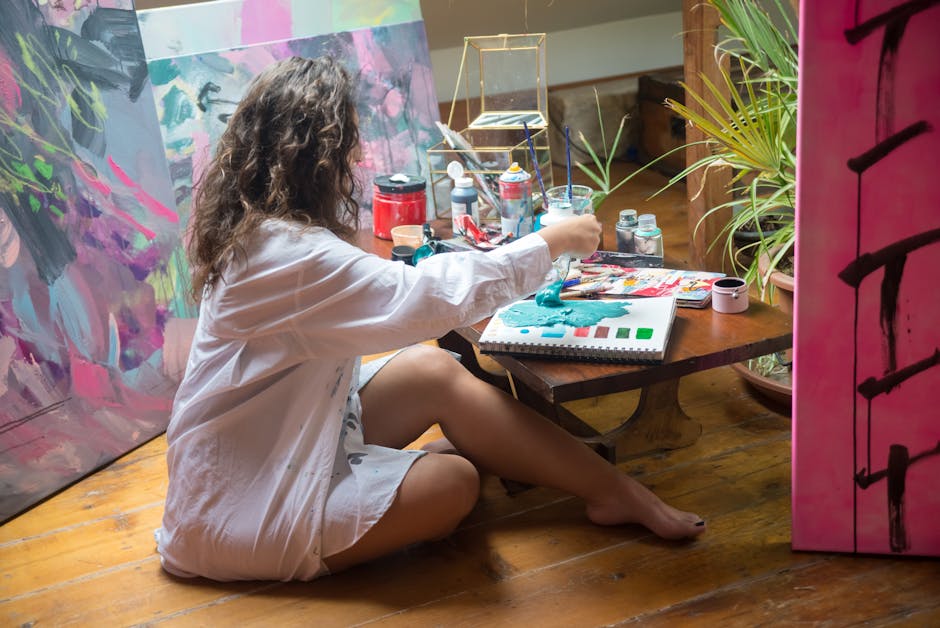 A female artist painting on canvas in a vibrant studio with art materials around.